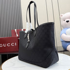 Gucci tote bag angled view in dark GG monogram canvas with double leather straps