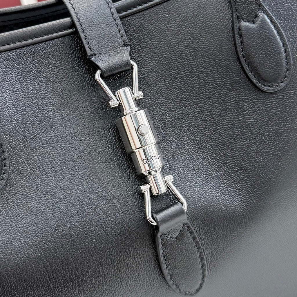 Gucci black leather tote bag close-up of front clasp and metal hardware