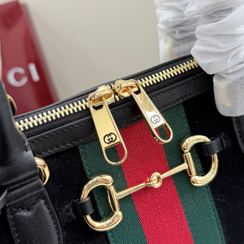 Gucci bag zipper pull detail with gold hardware and green-red-green web stripe