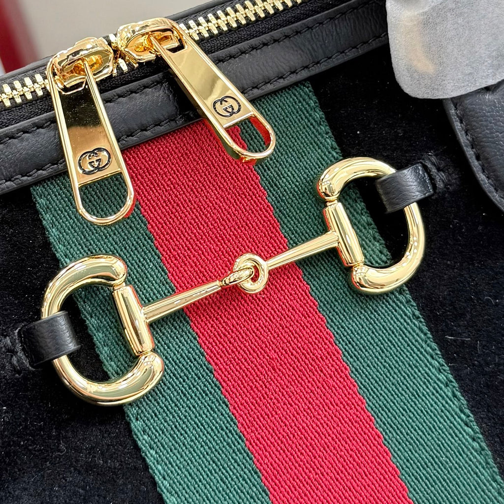 Gucci bag strap detail with gold hooks, green-red-green web stripe, and black leather