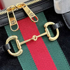 Gucci bag strap detail with gold hooks, green-red-green web stripe, and black leather