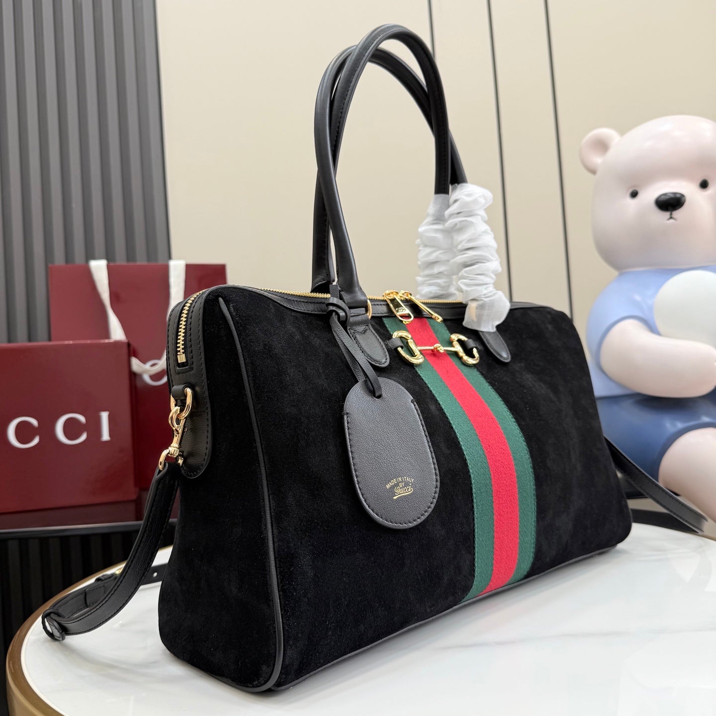 Gucci bag with black side profile, green-red-green stripe, zip top, gold-tone rings
