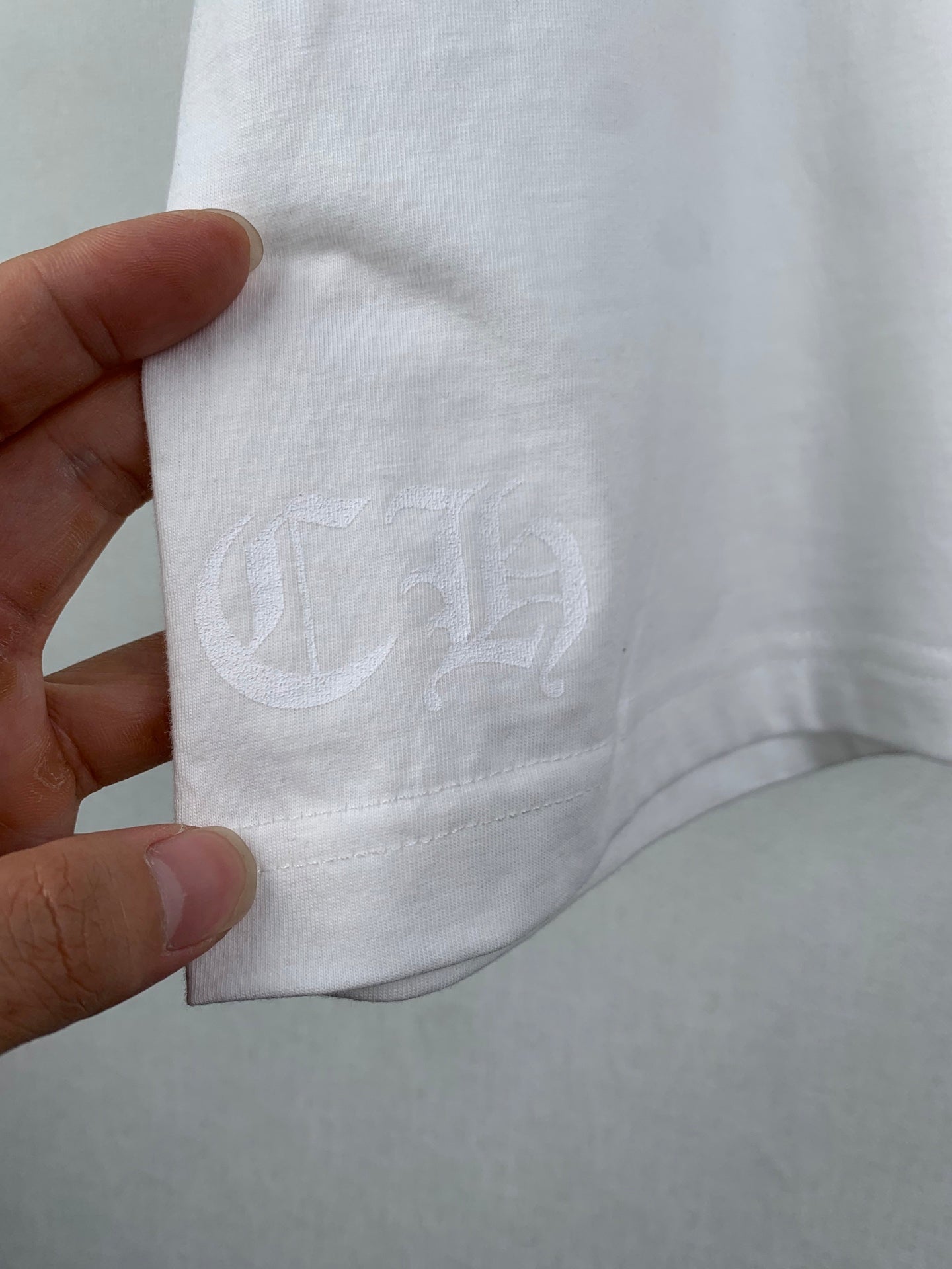 White T-shirt sleeve with embossed C logo near hem