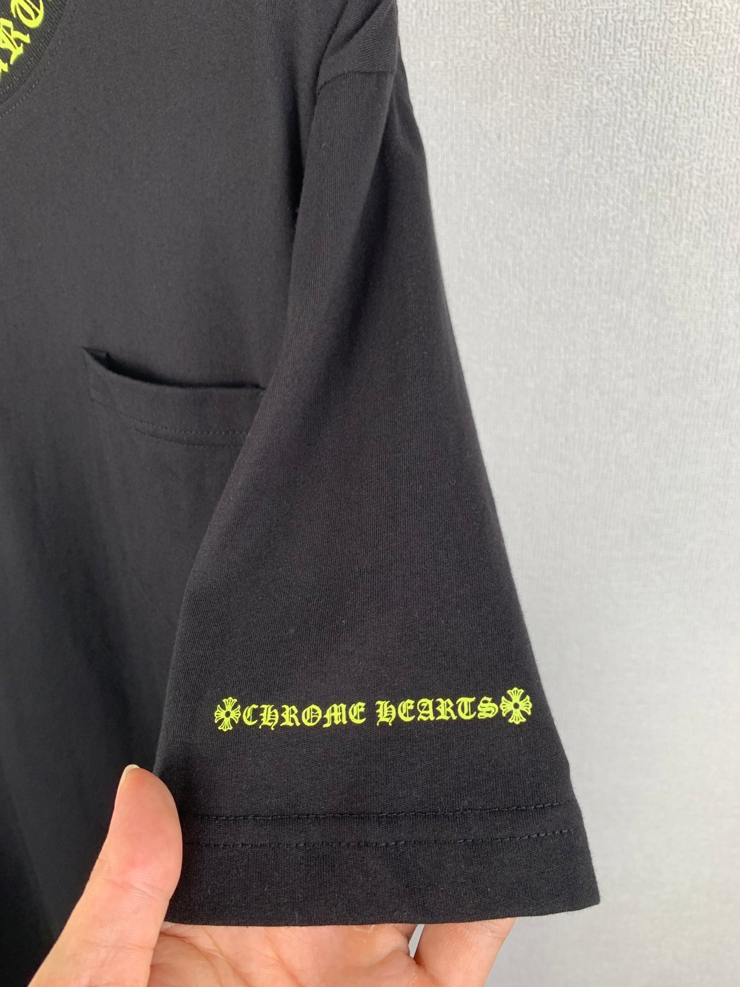 Black short-sleeve T-shirt with front pocket and neon green logo at hem