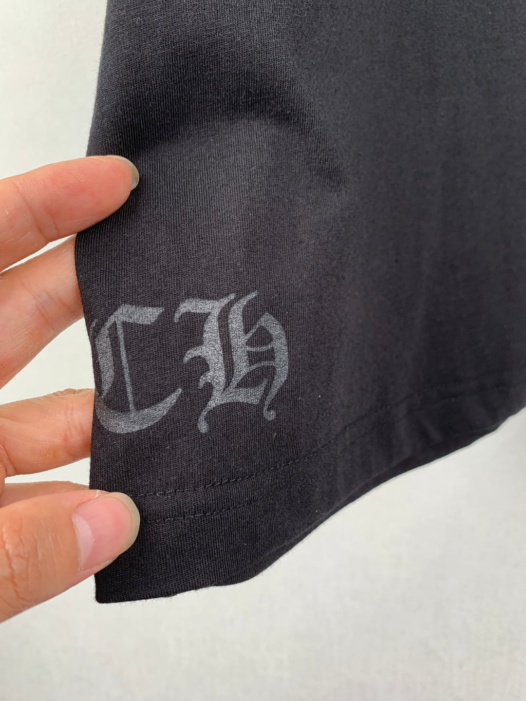 Black T-shirt fabric with gray printed symbol on sleeve