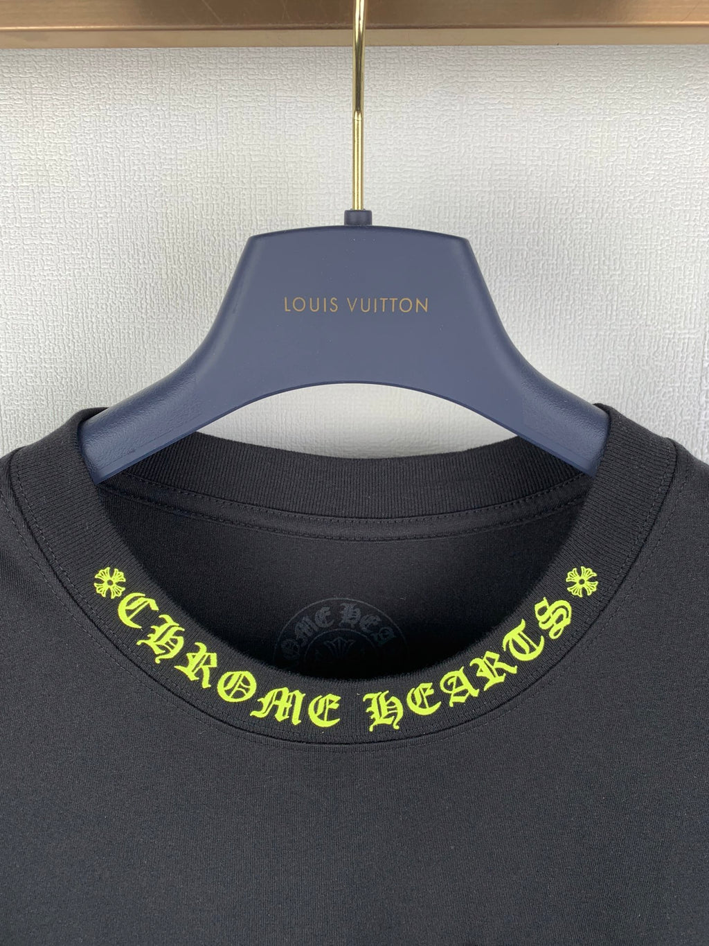 Black crew-neck T-shirt close-up with neon green graphic text at neckline