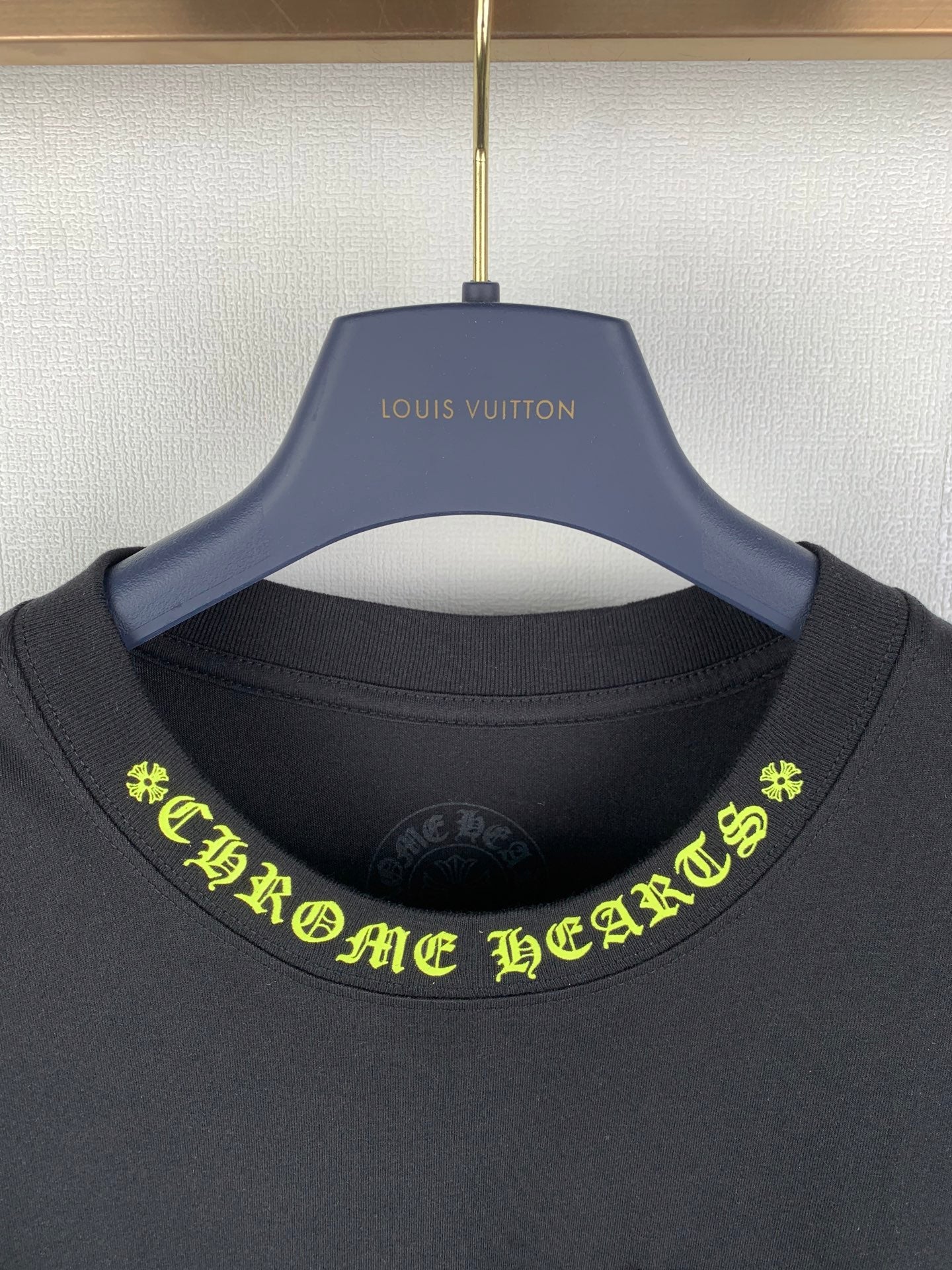 Black crew-neck T-shirt close-up with neon green graphic text at neckline