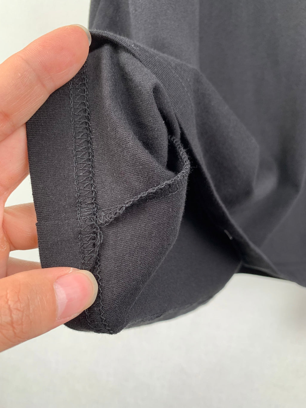 Black T-shirt sleeve cuff and side seam stitching close-up