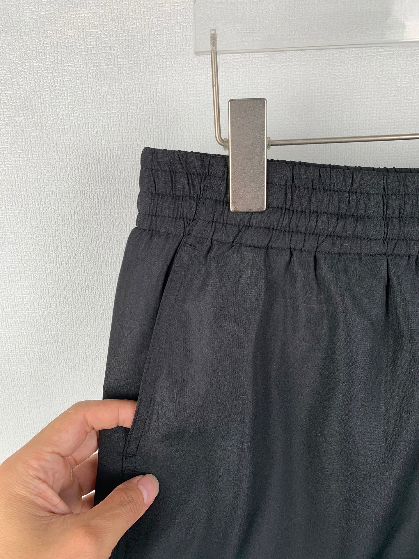 Louis Vuitton black shorts waistband close-up, fabric held by hand