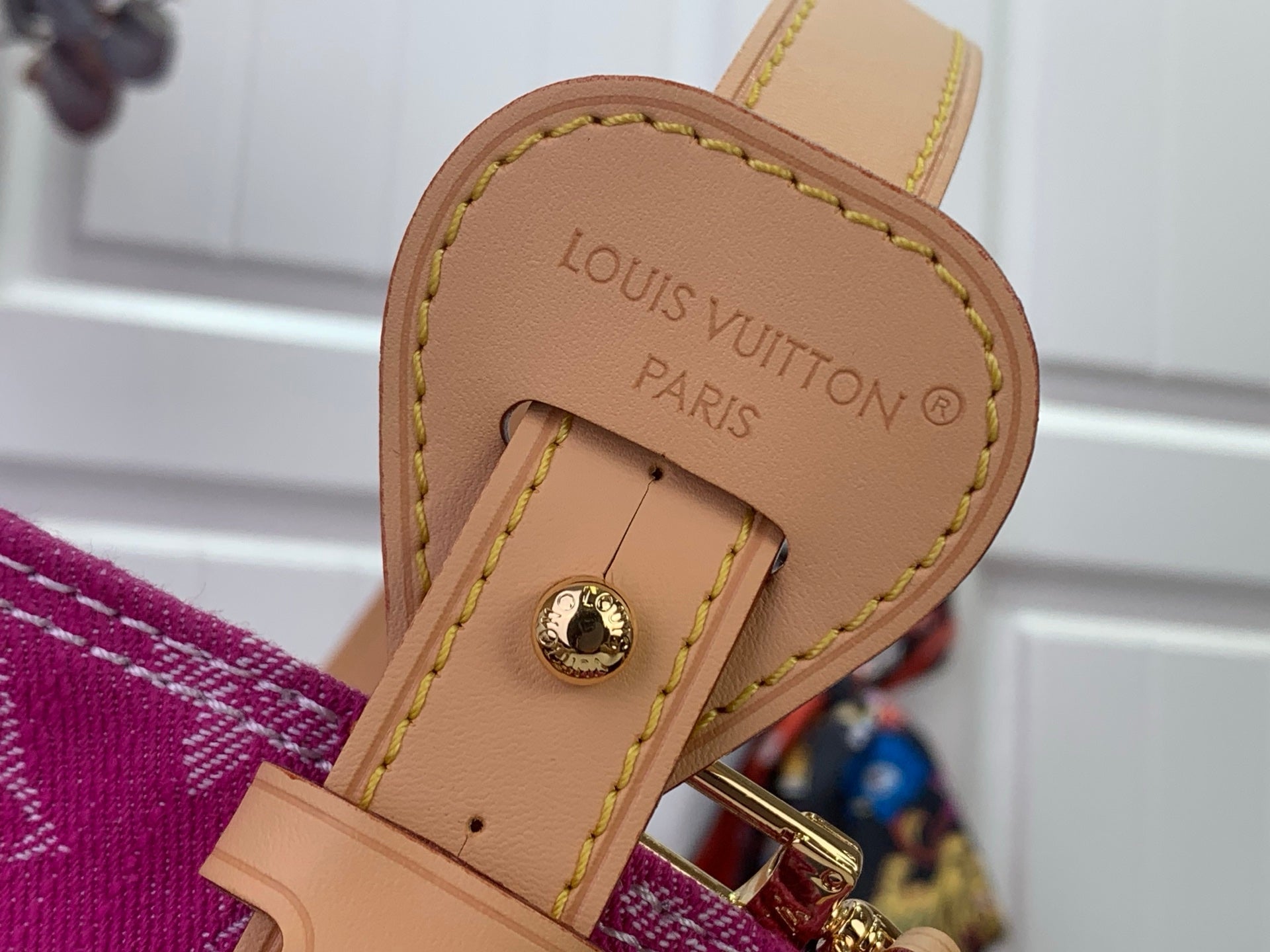 Tan leather logo patch with Louis Vuitton Paris stamp on purple monogram bag