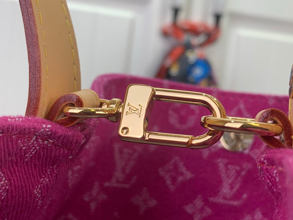 Gold clasp hardware on purple monogram bag with tan strap attachment