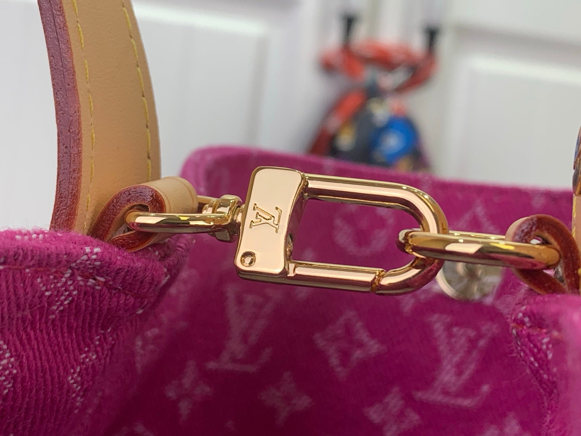 Gold clasp hardware on purple monogram bag with tan strap attachment