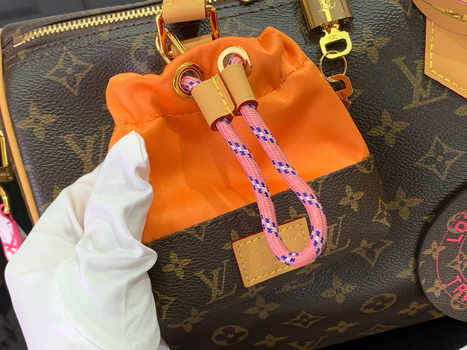 Louis Vuitton monogram bag with orange drawstring pouch and pink webbing strap