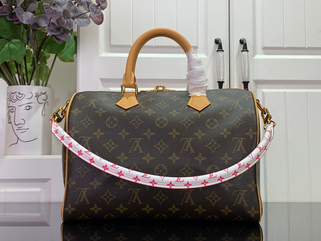Louis Vuitton monogram bag with tan handles and pink-and-red patterned strap trim