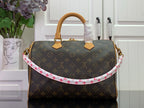 Louis Vuitton monogram bag with tan handles and pink-and-red patterned strap trim