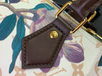 Brown leather luggage tag with gold snap button on floral handbag strap