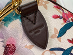 Brown leather strap tab with embossed lettering on floral handbag