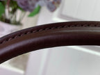 Close-up of brown leather handbag strap with smooth grain texture and stitching
