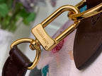 Gold clasp rings and hardware on brown leather strap over floral fabric