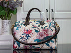 Floral handbag with white background, blue and pink flowers, brown handles, gold accents