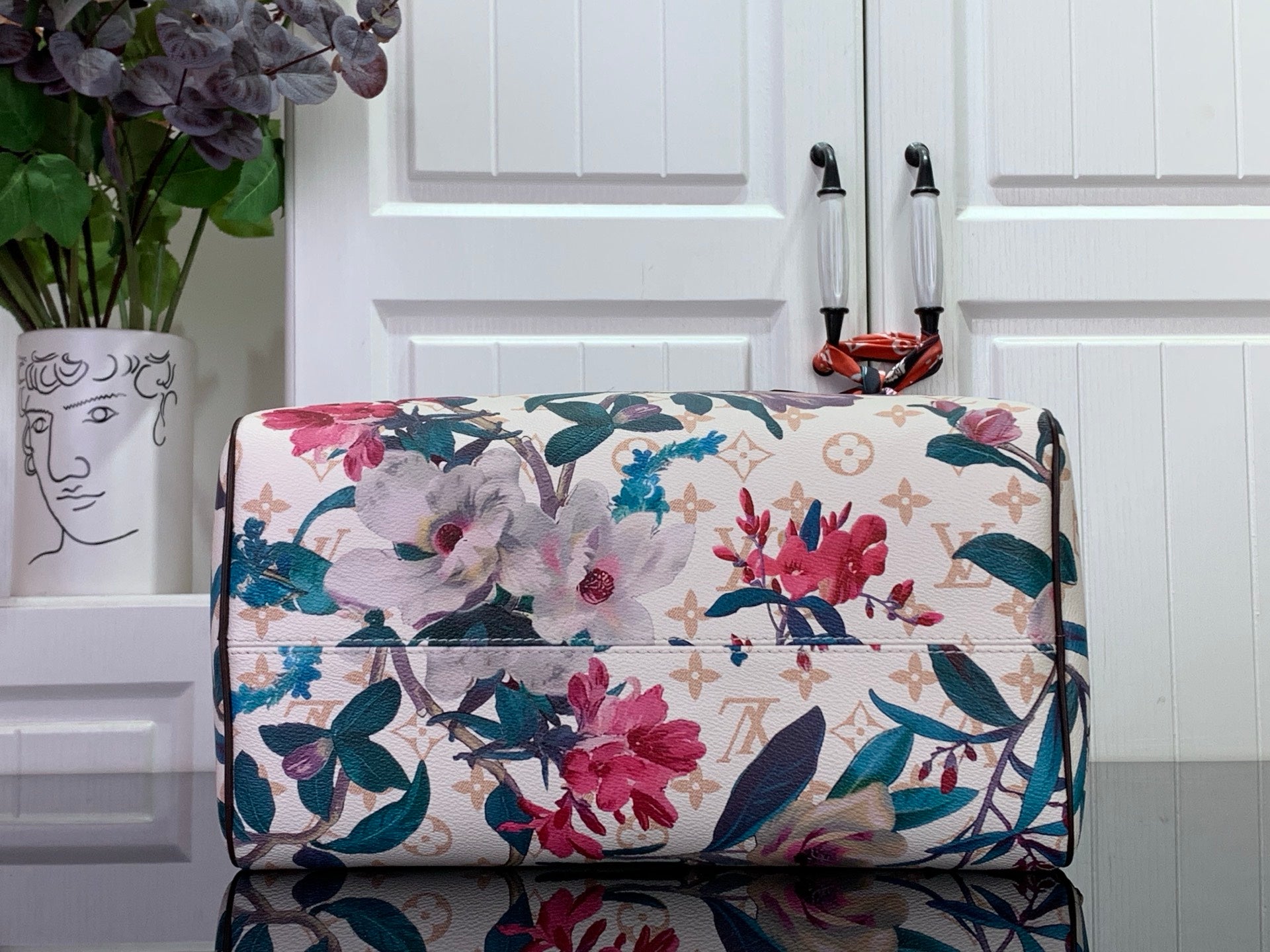 Floral duffel-style handbag with white base and multicolor flowers, brown trim