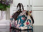 Floral handbag with white base and colorful blossoms, brown top handle, gold hardware