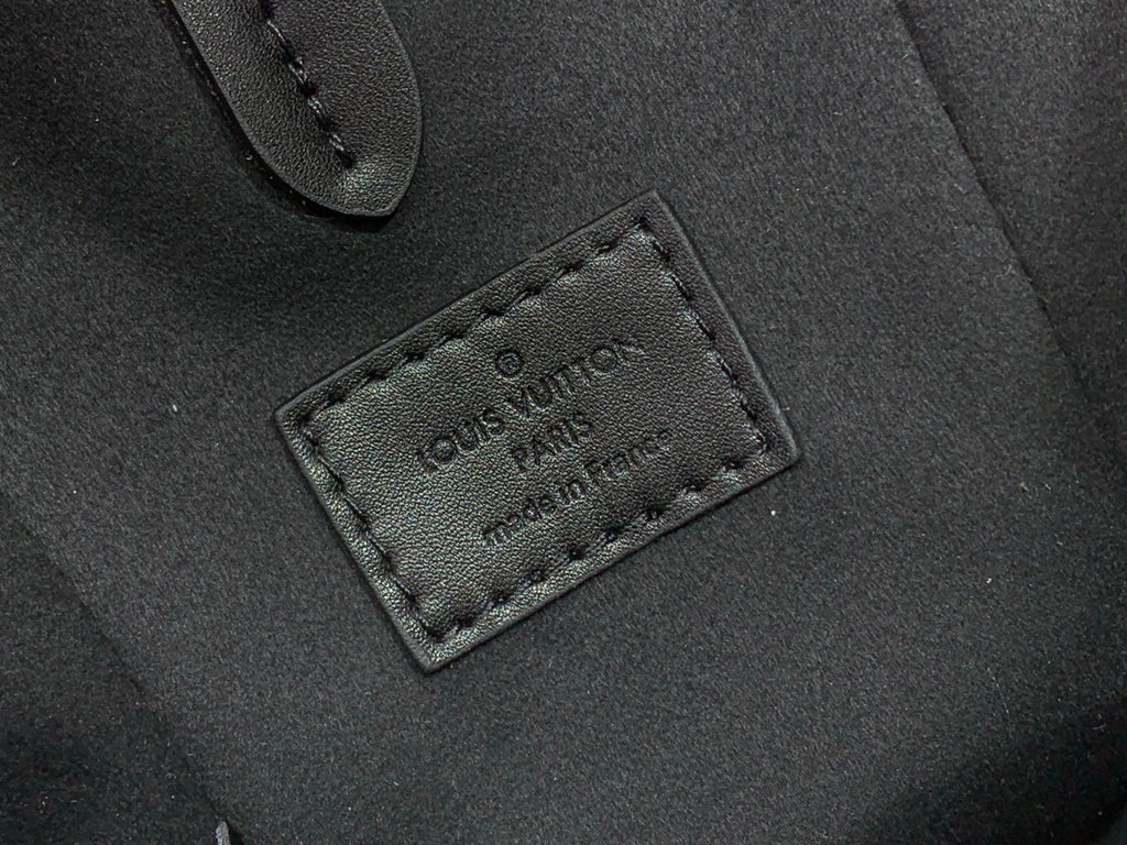 Louis Vuitton leather patch with embossed logo on dark bag