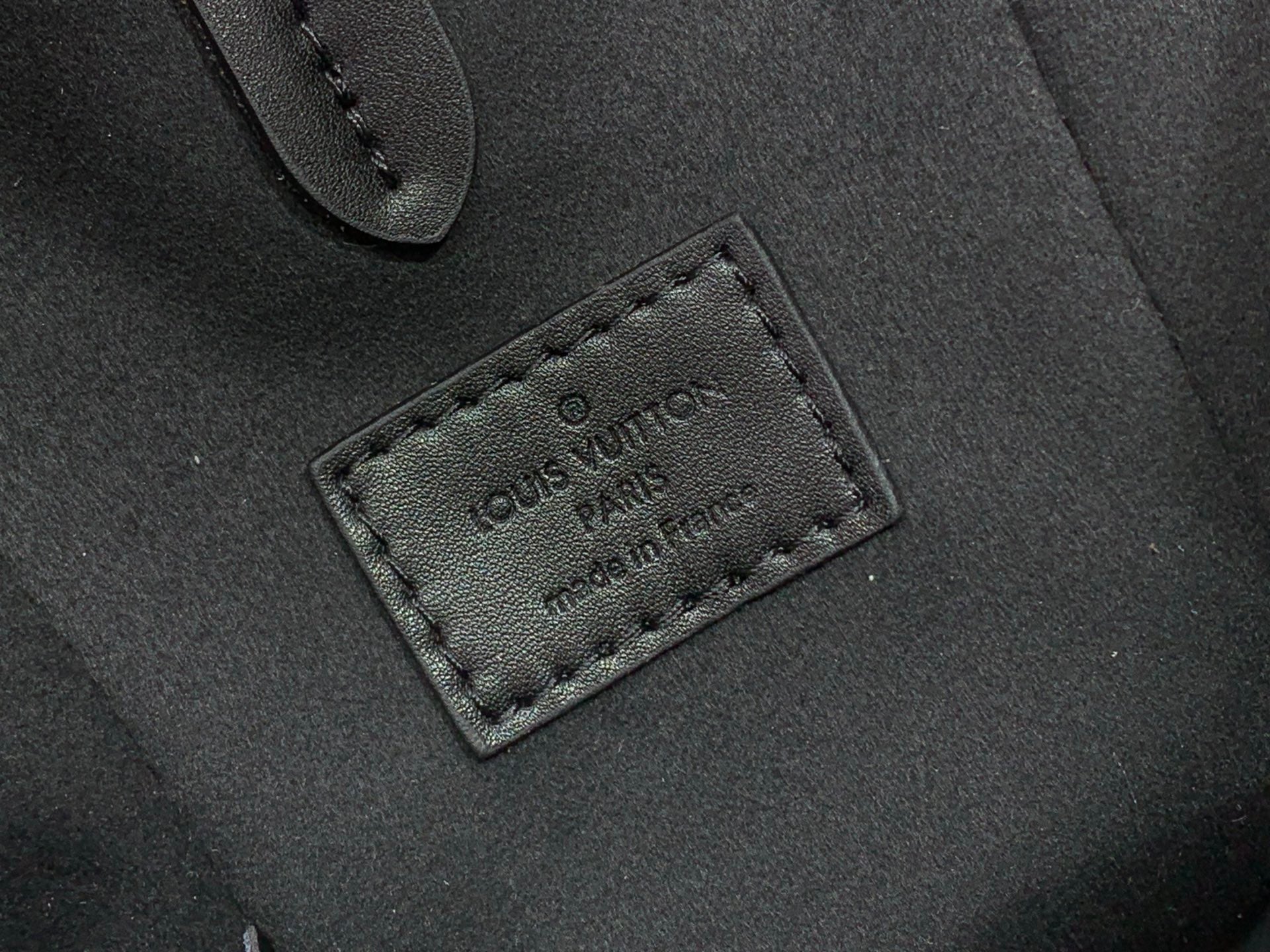 Louis Vuitton leather patch with embossed logo on dark bag