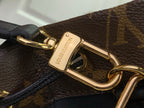 Louis Vuitton gold clasp detail on brown monogram bag, black strap