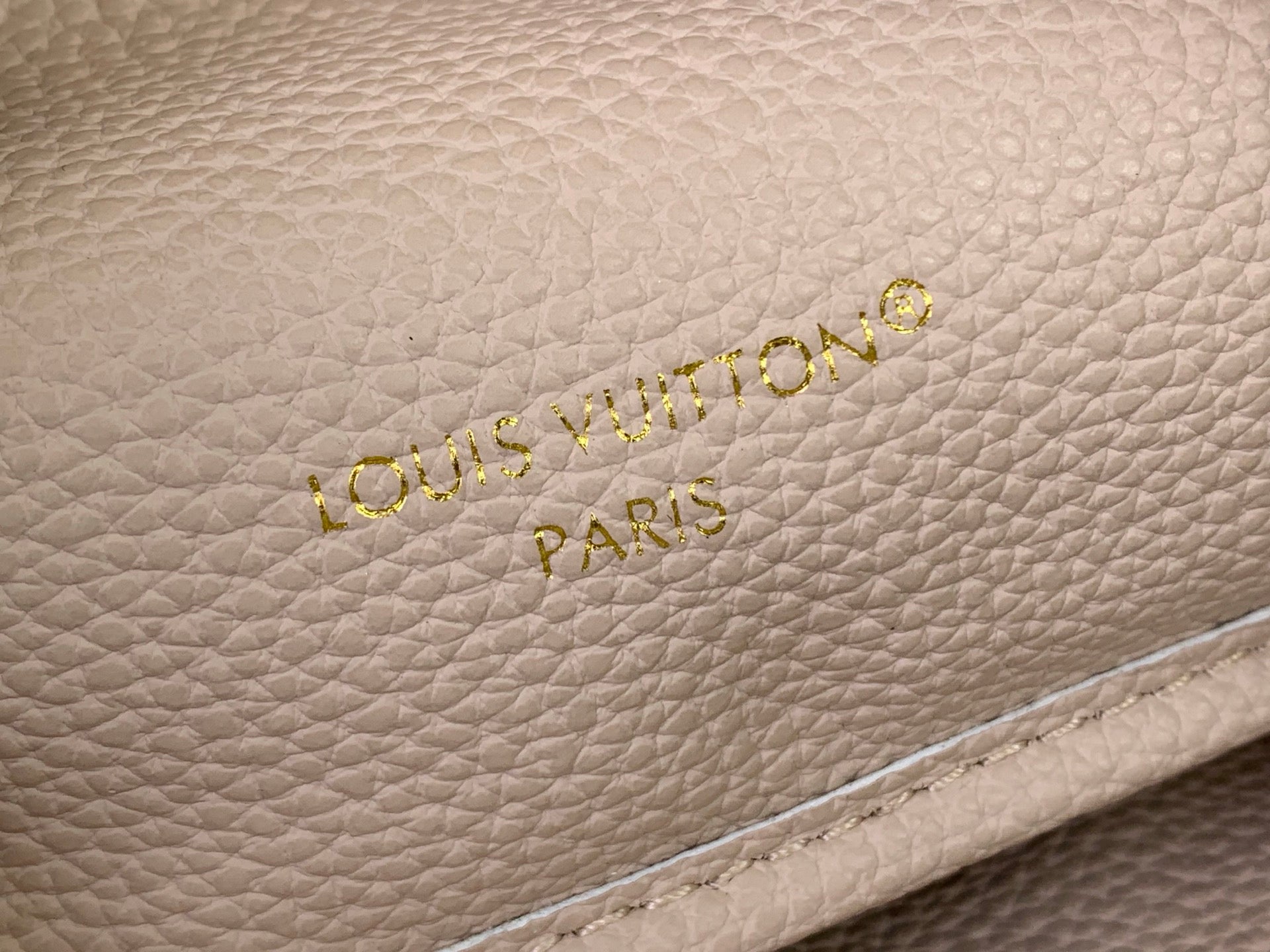 Light beige textured leather Louis Vuitton Paris logo with gold embossed letters