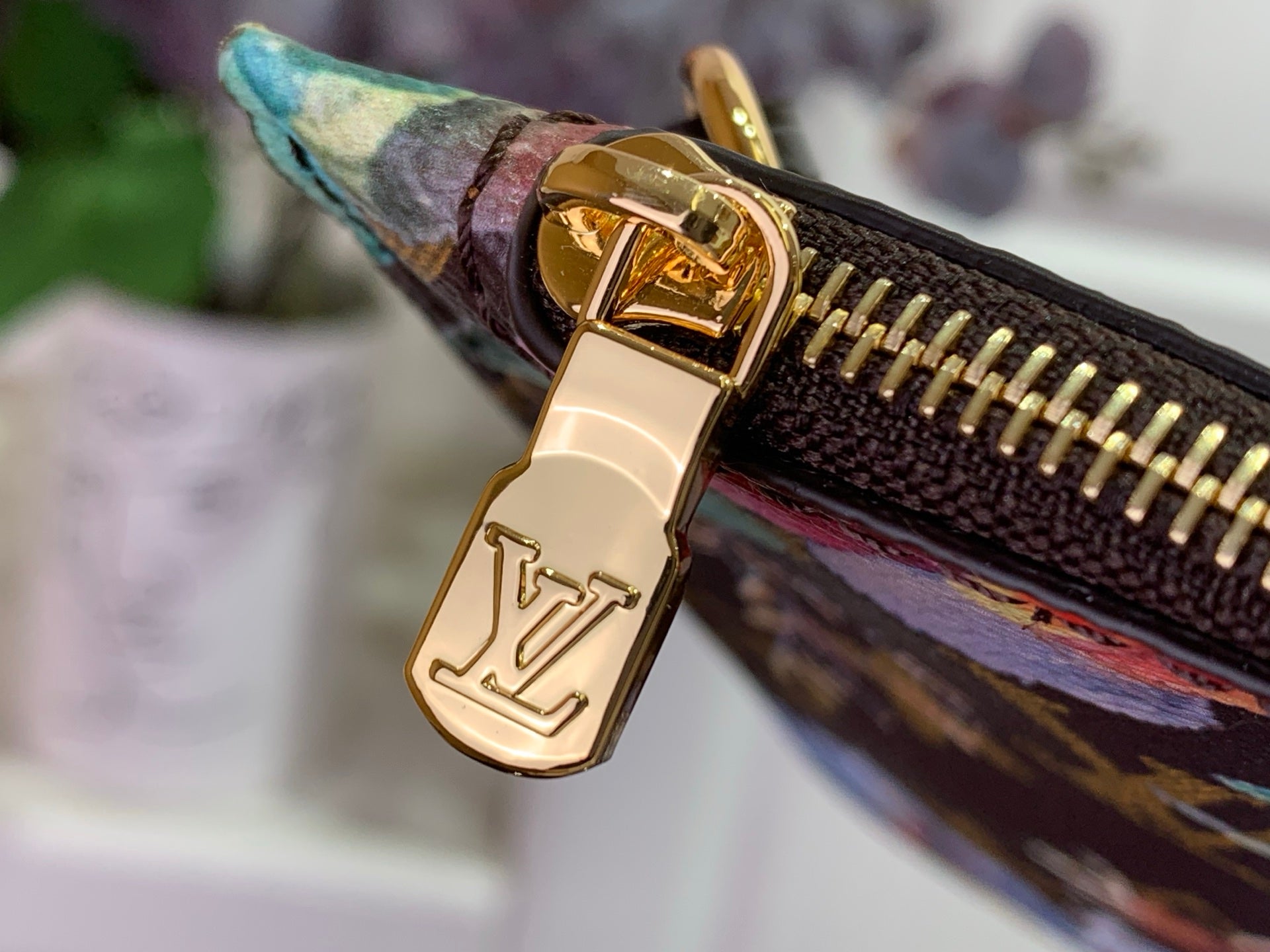 Gold-tone zipper pull with Louis Vuitton lock on floral monogram pouch