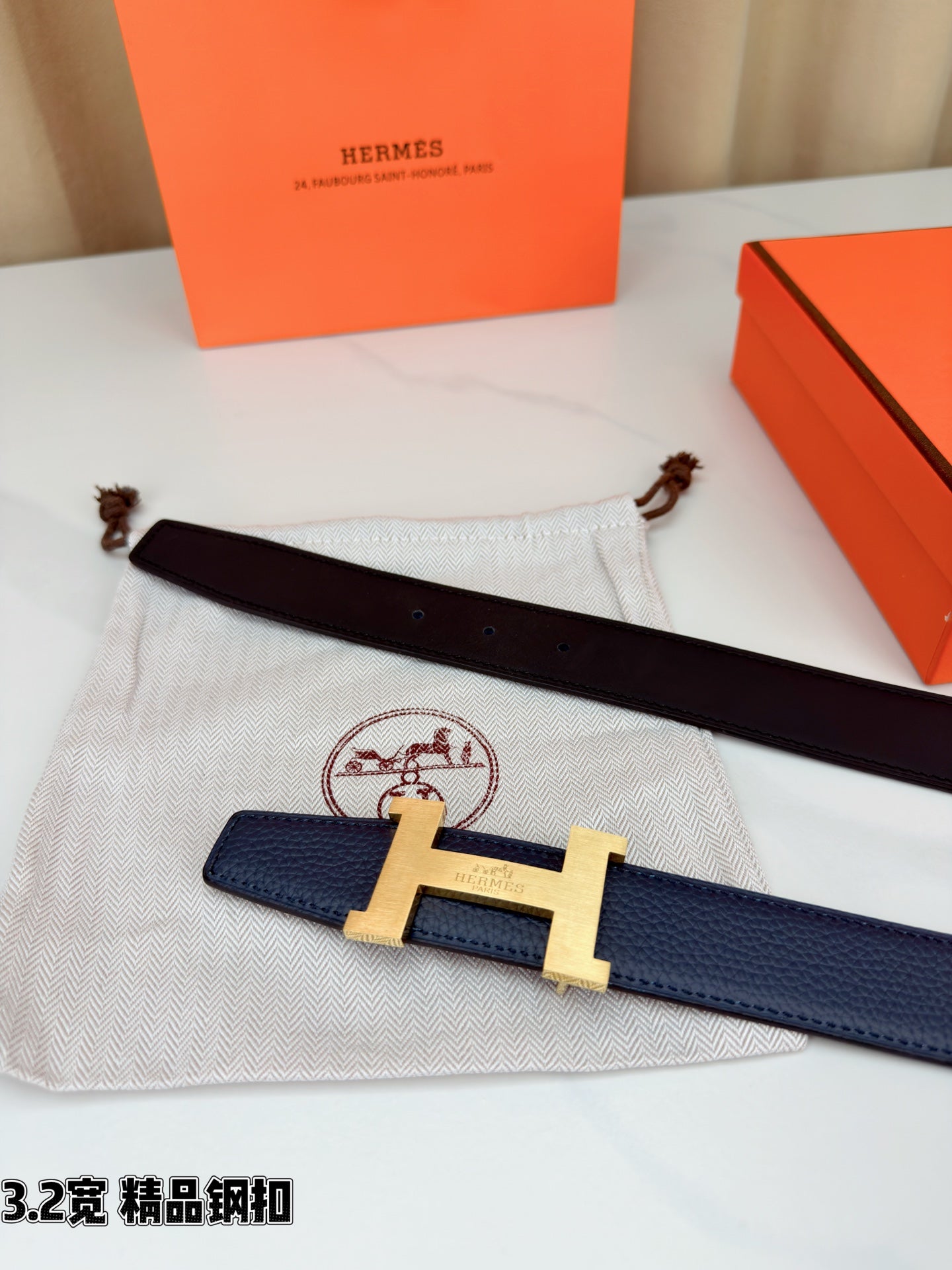 Dark blue leather belt with gold H buckle and dark leather underside on a pouch