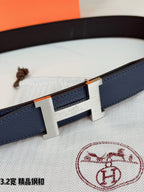 Close-up of dark blue leather belt with rectangular gold H buckle and engraved center