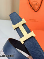 Detail view of gold H buckle on dark blue leather belt with embossed texture