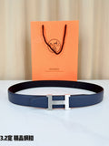 Dark blue leather belt with gold H buckle, laid flat on a white surface