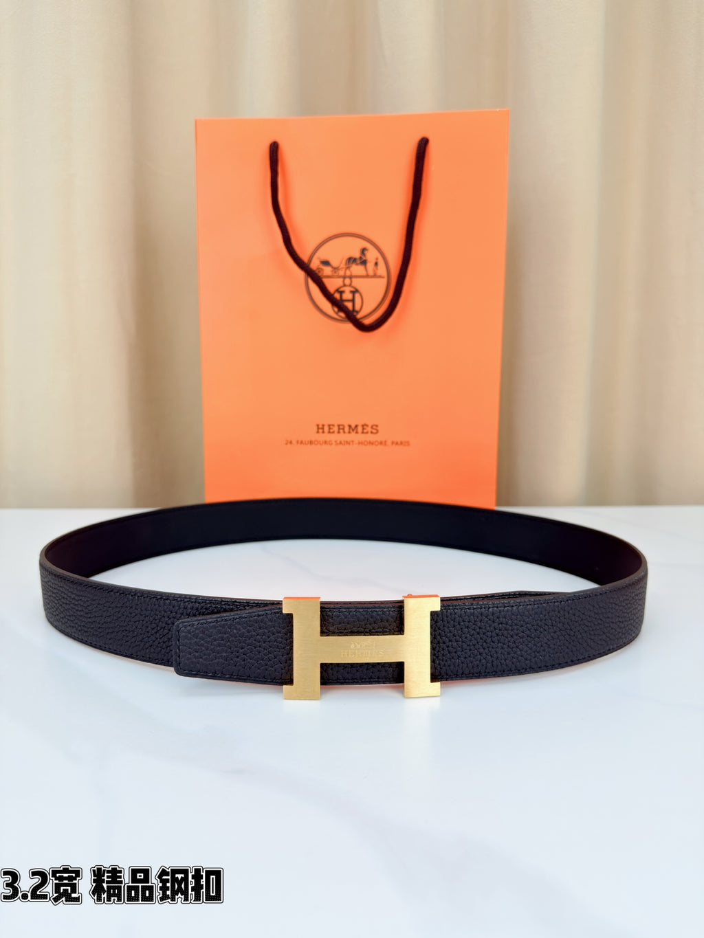 Leather belt with dark strap and gold-tone H buckle, shown flat with clasp centered.