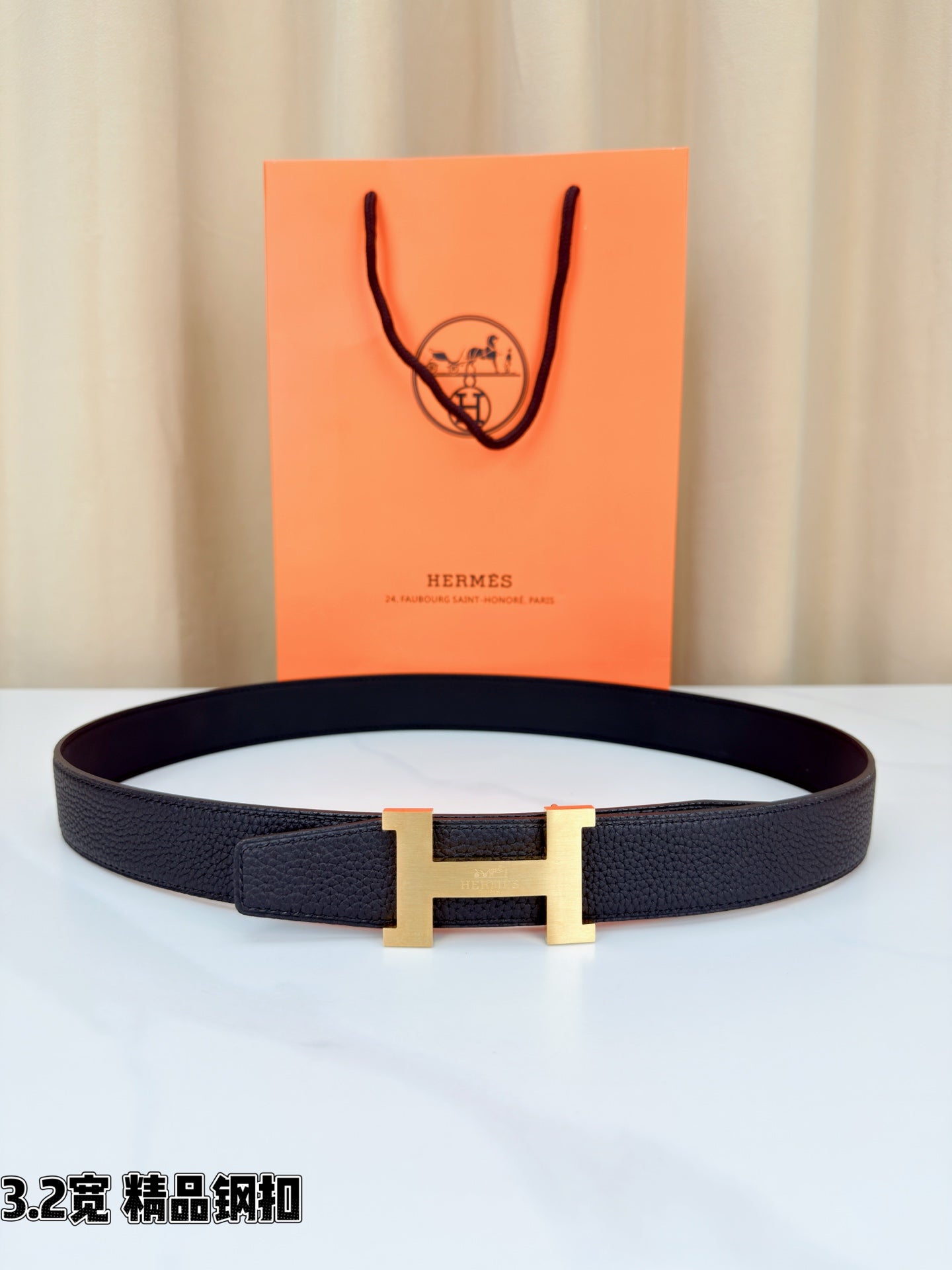 Leather belt with dark strap and gold-tone H buckle, shown flat with clasp centered.