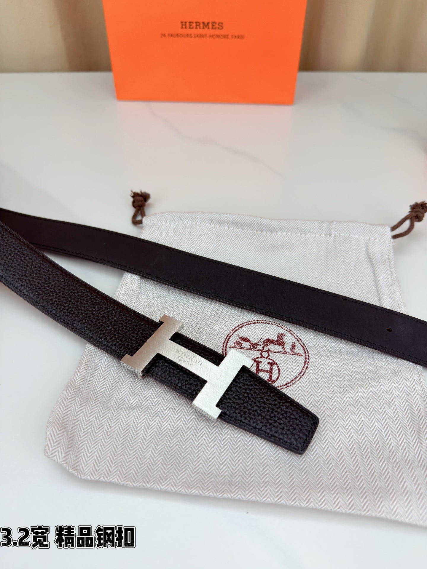 Dark leather belt with gold-tone H buckle, shown with strap ends and pouch.