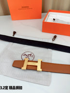 Brown leather belt lying flat with gold H buckle centered and one strap end visible.