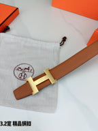 Brown leather belt angled close-up with gold H buckle and strap end detail.