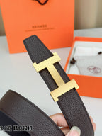 Dark brown leather belt with gold-tone H buckle, shown at angled close range.