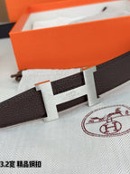 Dark brown leather belt buckle with gold-tone H, clasp over textured strap.