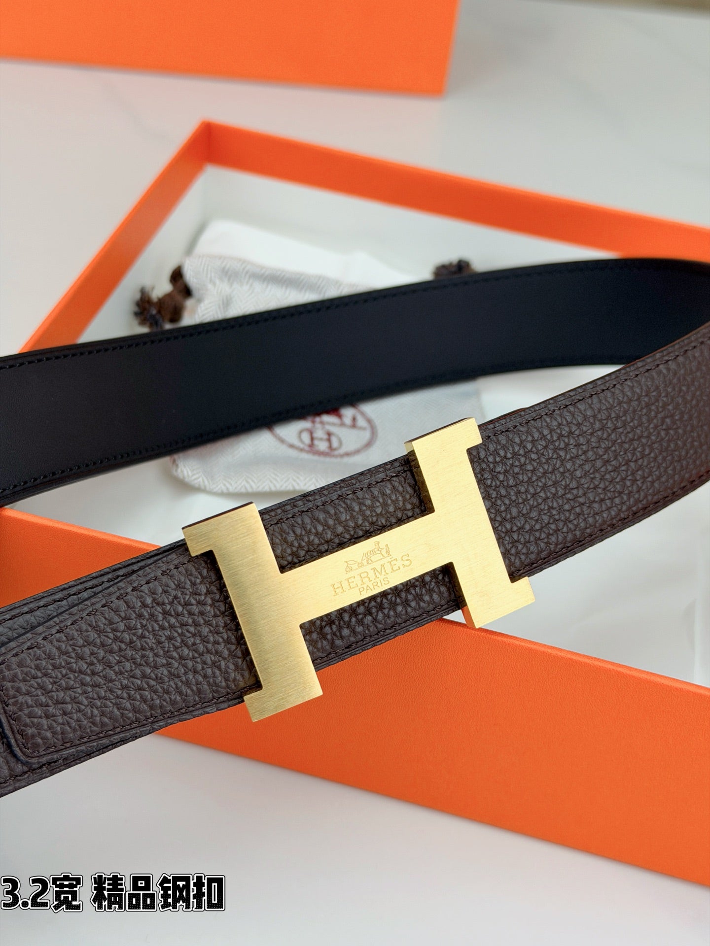 Dark brown leather belt with gold-tone H buckle and textured strap detail.