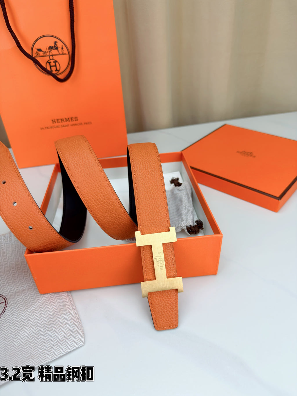 Orange leather belt with metal H buckle and matching keeper, styled in gift box