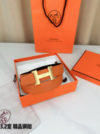 Orange leather belt with metal H buckle displayed in open gift box