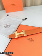 Orange leather belt with metal H buckle, placed on orange presentation box