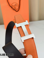 Orange leather belt with gold-tone H buckle detail, held in hand