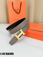 Grey leather belt with gold-tone H buckle, strap laid over box