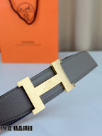 Grey leather belt detail showing gold-tone H buckle on textured strap