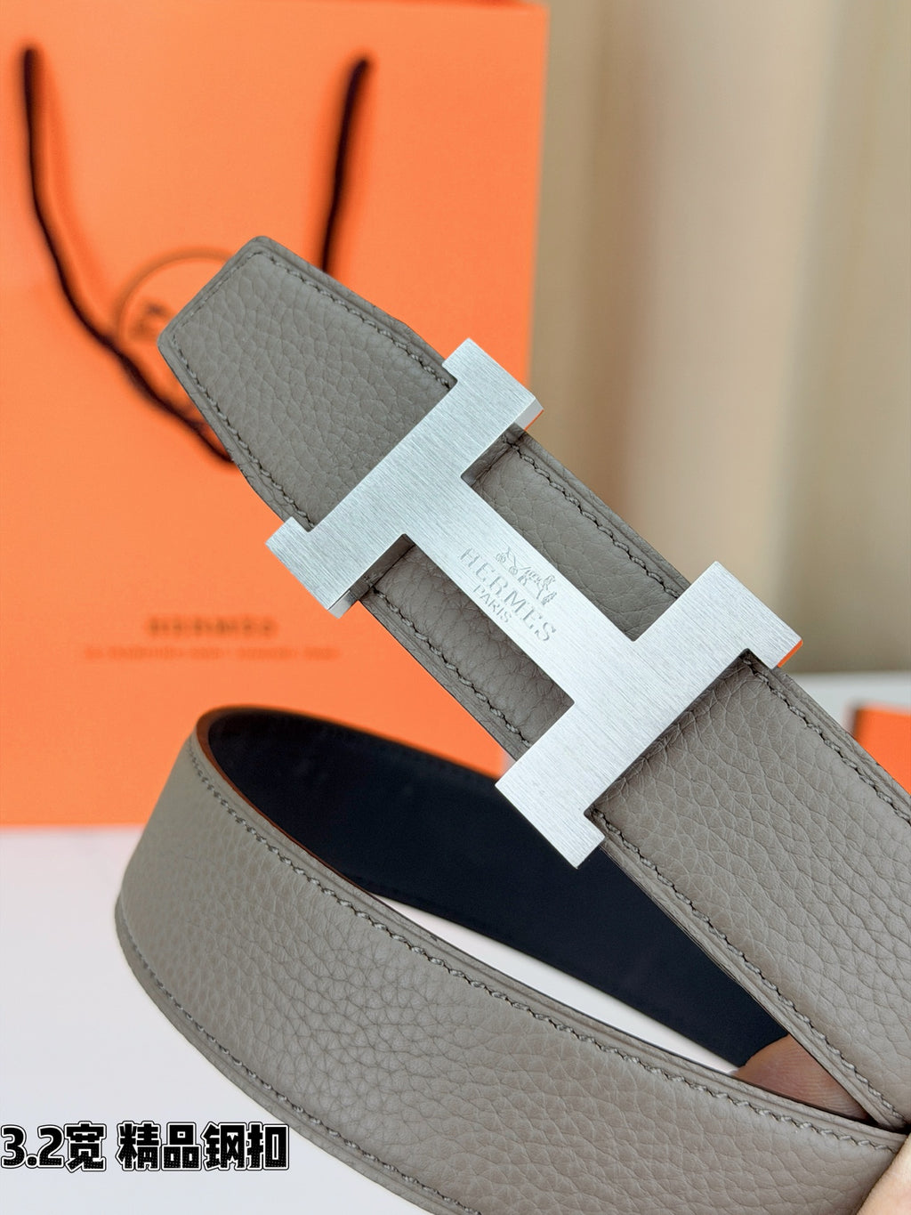 Grey leather belt buckle detail with silver-tone hardware backing